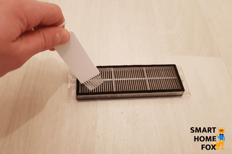 Cleaning the HEPA filter of a robot vacuum with a cleaning brush